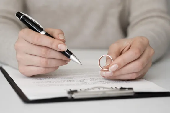 mujer firmando divorcio matrimonial con el amillo en la mano