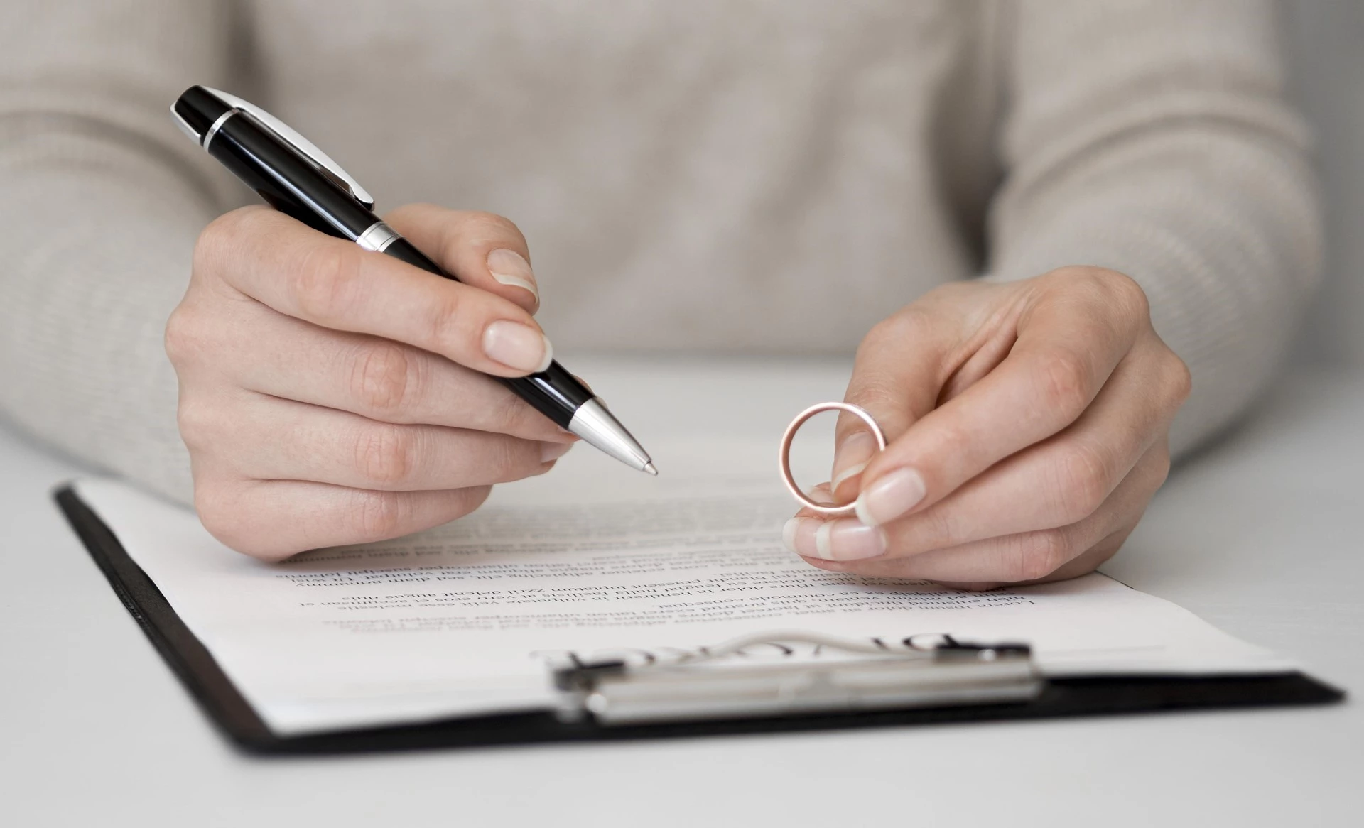 mujer firmando divorcio matrimonial con el amillo en la mano