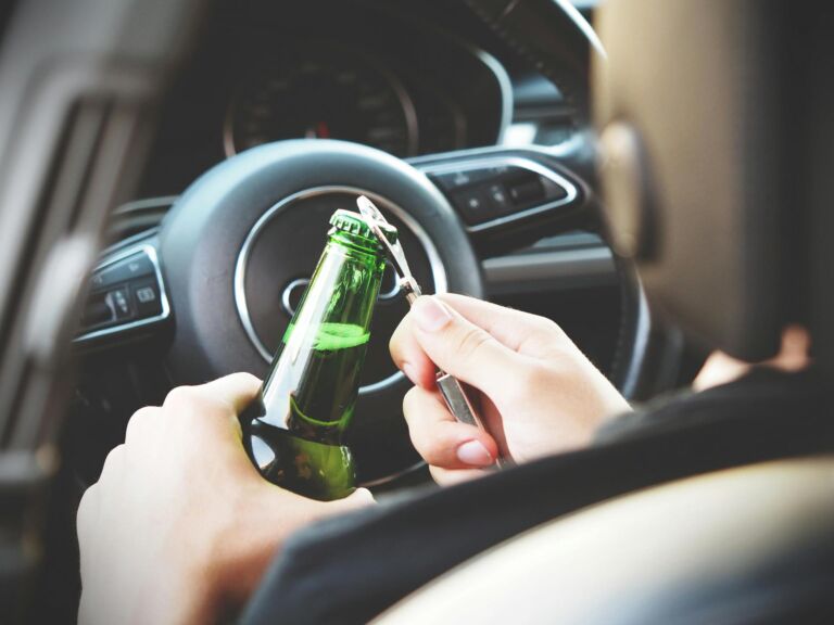 hombre al volante a punto de abrir una cerveza